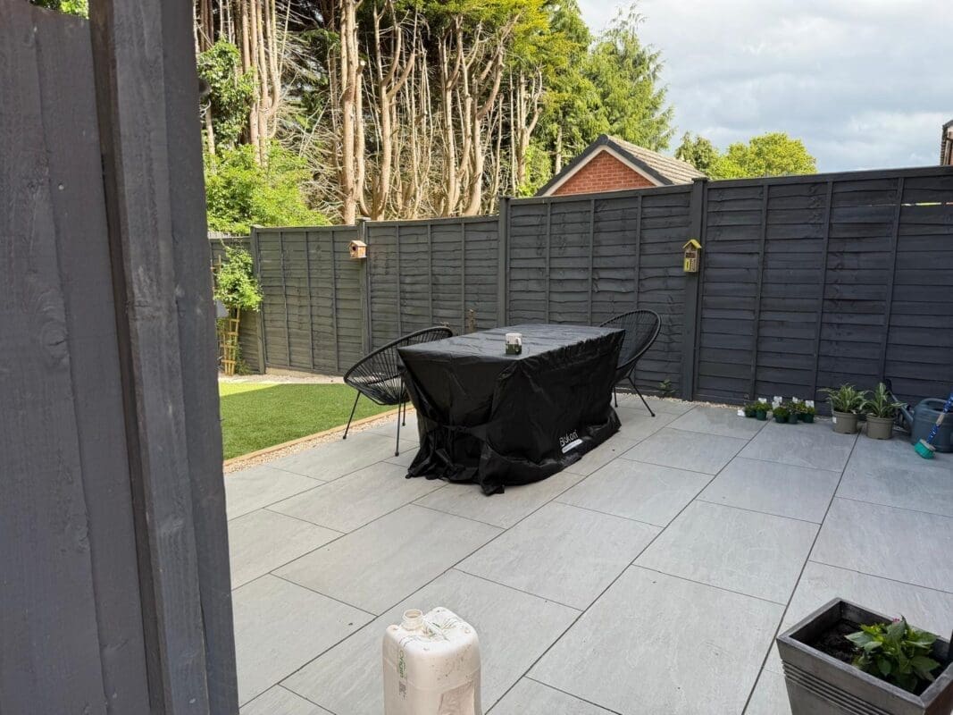 Completed residential garden transformation in Worcestershire — artificial lawn, children’s timber play area with slide, and grey porcelain patio with outdoor seating